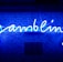 A bright blue neon sign spells out the word 'gambling' in cursive script. The background features a textured wall covered in domino tiles, also illuminated by the blue light, creating a vivid and visually striking scene.